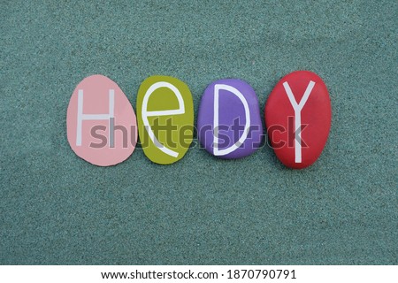 Hedy, German given name composed with multi colored stone letters over green sand
