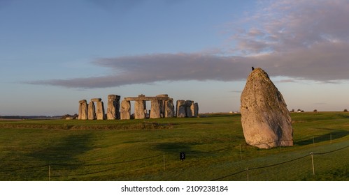The Heel stone with bird perched at the historical landmark of Stonehenge in the background panorama shot