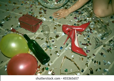 Heels, balloons, sparkles and bottle on the floor after party