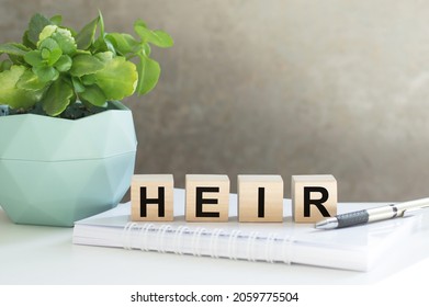 HEIR word made with building blocks on the table next to a flower in a pot and a notebook with a pen - Shutterstock ID 2059775504