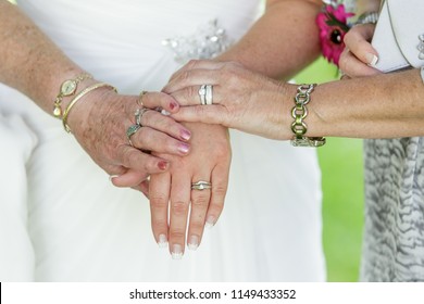 Heirloom, Wedding Photo Close Up Of The Hands Of Three Generations Of Women In A Family, Showing Their Wedding And Engagement Rings Set Against The Brides Dress.