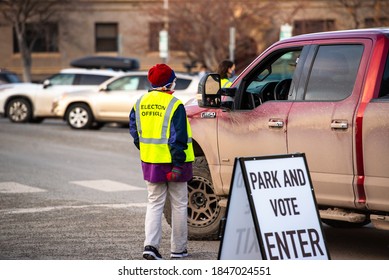 Helena, Montana / November 3, 2020: Woman Poll Worker Helping Voter At Polling Station, Park Vote In Truck, Presidential Election Day Voting, People In Street During Coronavirus Pandemic Covid 19