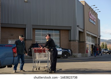 Helena, Montana / US - March 24, 2020: A Smiling Police Officer Helping An Elderly Man Unload His Groceries And Return His Shopping Cart. Extra Costco Police Security During Coronavirus Pandemic. 