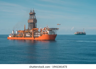 Helicopter approaching to deep water drill ship with Production Floating Liquified Natural Gas facility in the background
