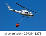 Helicopter with a Bambi bucket filled with water to fight a forest fire