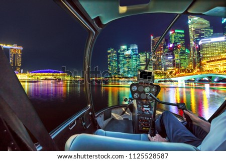 Helicopter cabin interior flying on Panorama of Singapore buildings and skyscrapers of downtown reflected in the sea. Singapore scenic flight by night. 