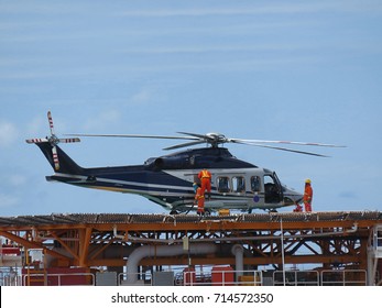 Helicopter or chopper land at oil and gas platform area for get and sent passenger from onshore hangar to offshore platform. Ground staff fill the gas tank in helicopter.                           