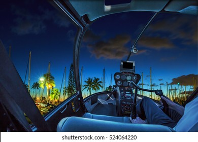 Helicopter cockpit flies in Ala Wai Harbor, Honolulu by night, Oahu, Hawaii, with pilot arm and control board inside the cabin.