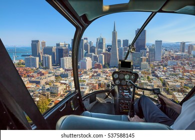 Helicopter cockpit flies in San Francisco Financial District Downtown, California, United States, with pilot arm and control board inside the cabin in a sunny day.