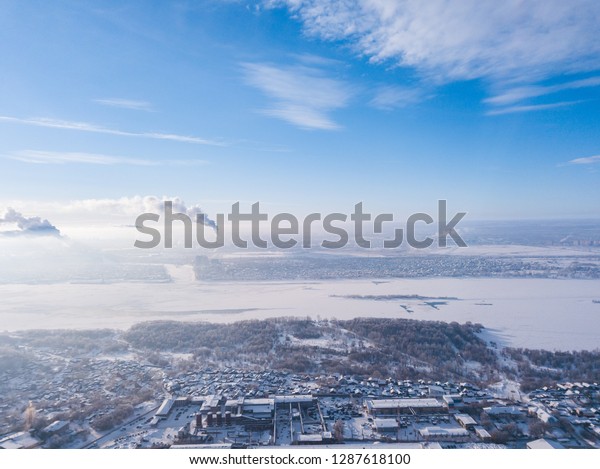 Helicopter drone shot. Aerial photography of a\
 river with bridge, modern city over an area, a large crossroads,\
high-rise buildings and cars in winter\
day