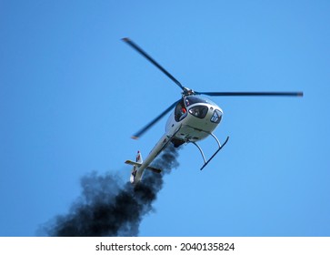 Helicopter with engine problems. Black smoke comes out of the helicopter's engine and the helicopter tries to make an emergency landing. Small helicopter.