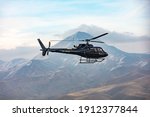 Helicopter in flight. Black Helicopter is flying between mountains peak, winter time. A beautiful Caucasian mountain in the background scene. Luxury Lifestyle, Vacation tour on helicopter