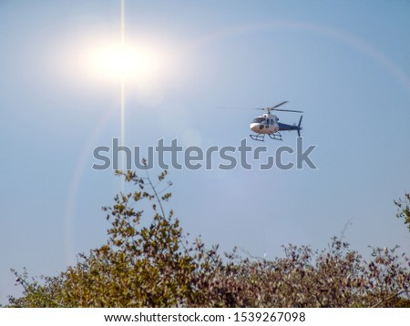 Helicopter flying low altitude over the African bush, giving a tour to the safari tourists, sunshine