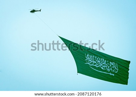 Helicopter flying with the Saudi flag during the Jeddah Air show celebrating the national day. The flag contains the Arabic decleration of faith 