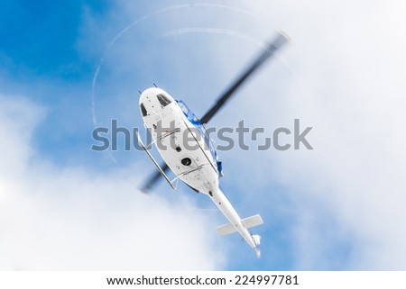 Helicopter flying under sky covered with clouds
