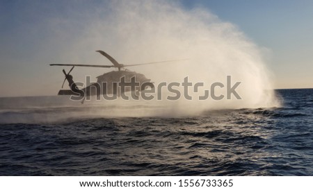 Helicopter hovering over water inserting a team. 
