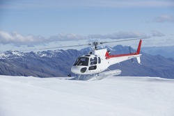 Helicopter Landing On Snowy Mountain Top Against Blue Sky