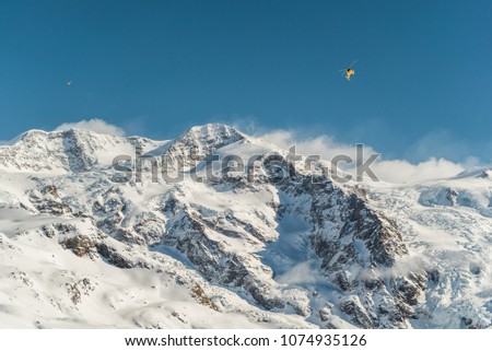 Helicopter over mountain peaks snd glacier. Transporting heliskiing clients to the mountains. Heli-skiing in Monte Rosa. Italy. Extreme winter sport. Heliski in high mountains. Freeride ski. 