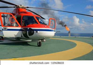The helicopter park on oil rig to pick up worker with gas flare and blue sky backgroung