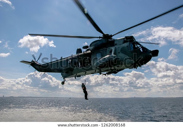 Helicopter rescue mission in difficult stormy\
weather at sea. Military helicopter in Baltic sea, Latvia; Army\
helicopter training in Baltic sea. Rescue mission in sea with\
helicopter.