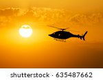 Helicopter silhouette across sunset