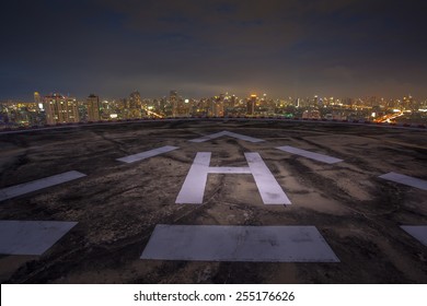 Helipad On The Roof Of A Skyscraper At Night With Cityscape View