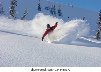 heliski snowboarding. freerider in a bright suit rides snowboarding with large splashes of snow on a sunny day. Young snowboarder. concept snowboard. big swirls of fresh snow in Good powder day - Powered by Shutterstock