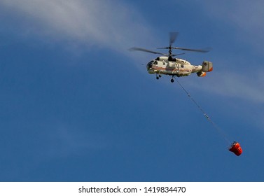 Helitack With A Helicopter Bucket Flying In Blue Sky. Almaty, Kazakhstan. Selective Focus