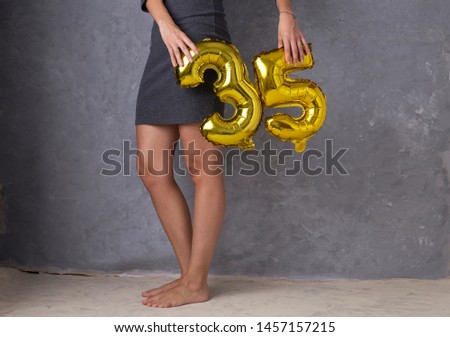 Helium balloons number 35, woman holding two gold foil balloons