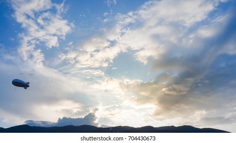 Helium Blimp Advertising Balloon Floating Sunset Sky And Mountain Background