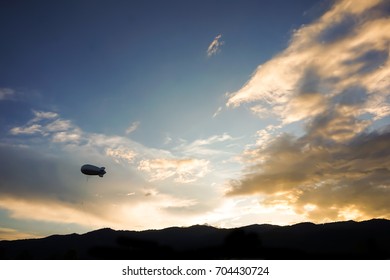 Helium Blimp Advertising Balloon Floating Sunset Sky And Mountain Background