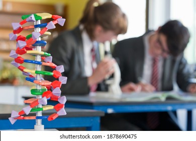 Helix DNA model with high school student conducting a scientific experiment in the background. - Powered by Shutterstock