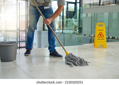 Hell leave that floor spotless. Shot of an unrecognizable man mopping the office floor. - Powered by Shutterstock