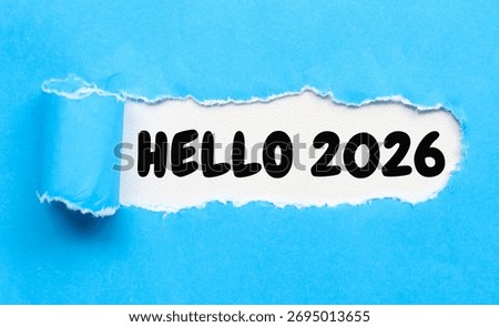 Hello 2026 text on torn blue paper. A creative image featuring the words “HELLO 2026” revealed through a torn blue paper with a white background.