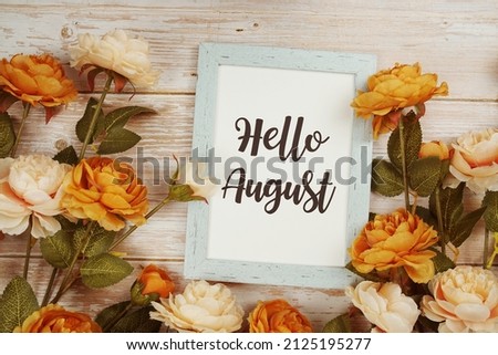 Hello August typography text with flower decoation on wooden background
