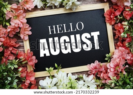 Hello August typography text written on wooden blackboard with flower bouquet decorate on wooden background