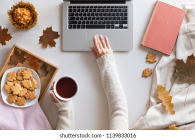 Hello Autumn flat lay background. Top view of workspace or office desk with laptop, tea or coffee cup, maple leaves, vintage book and honey biscuits and cookies. lish office desk. - Powered by Shutterstock