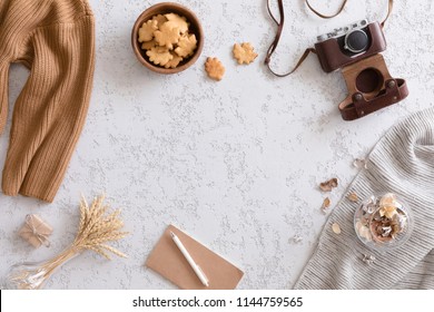 Hello Autumn flat lay background. Top view of workspace or office desk with vintage photo camera, sweater, cup of coffee, honey cookies, flowers and gold ears of wheat on textured white background - Powered by Shutterstock