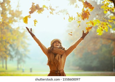 Hello autumn. happy elegant woman in sweater, skirt, hat, gloves and scarf outdoors in the autumn park enjoying autumn and catching falling yellow leaves. - Shutterstock ID 1558600097