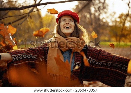 Hello autumn. happy modern woman in red hat with scarf rejoicing in the city park.