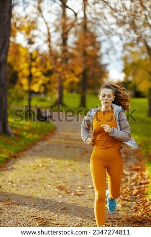 Hello autumn. middle aged woman in fitness clothes in the park running.