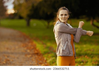 Hello autumn. modern female in fitness clothes in the park stretching. - Shutterstock ID 2366532711