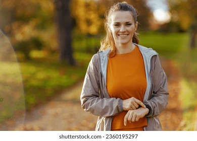 Hello autumn. Portrait of happy fit woman in fitness clothes in the park sport tracker. - Powered by Shutterstock