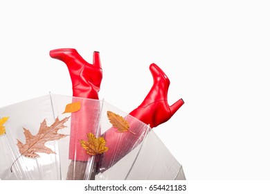 Hello autumn season. Red rubber high heels boots with umbrella and autumn leaves isolated on light background