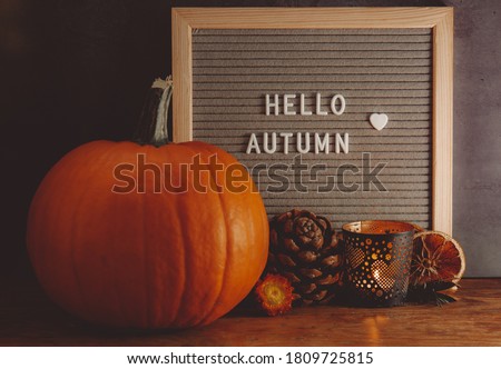 Hello Autumn sign. Autumn mood board. Autumn composition with pumpkin, pine, candle and message board. Cozy autumn mood. 