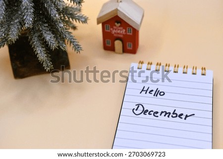 hello december write next to snowy tree and moder house 