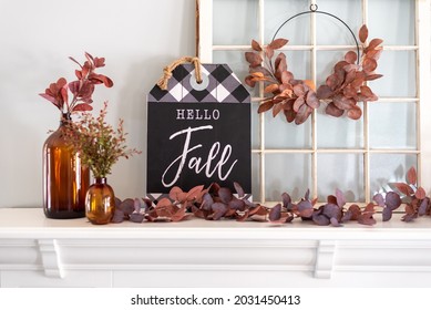 Hello fall sign and amber glass bottles on a white mantel decorated for Fall