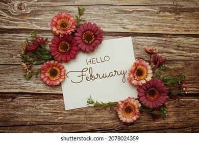 Hello February typography text with flowers on wooden background - Shutterstock ID 2078024359