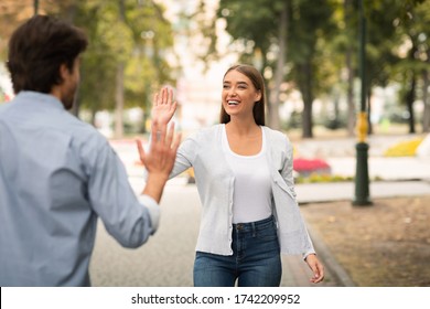 Hello Greeting. Girl Waving Hand Meeting Friend Guy Walking Outdoors In Park. Selective Focus