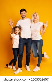 Hello. Happy Family Waving Hands Over Yellow Background In Studio. Full Length